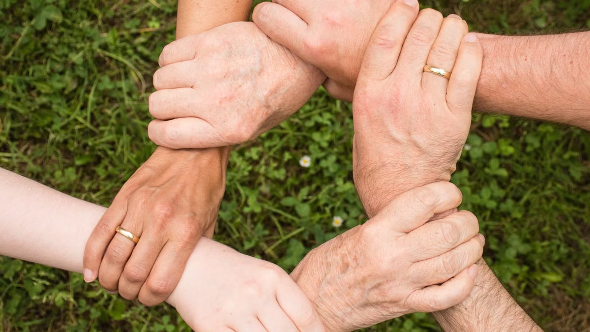 Close-up of diverse hands forming a connection, symbolizing teamwork and unity outdoors.